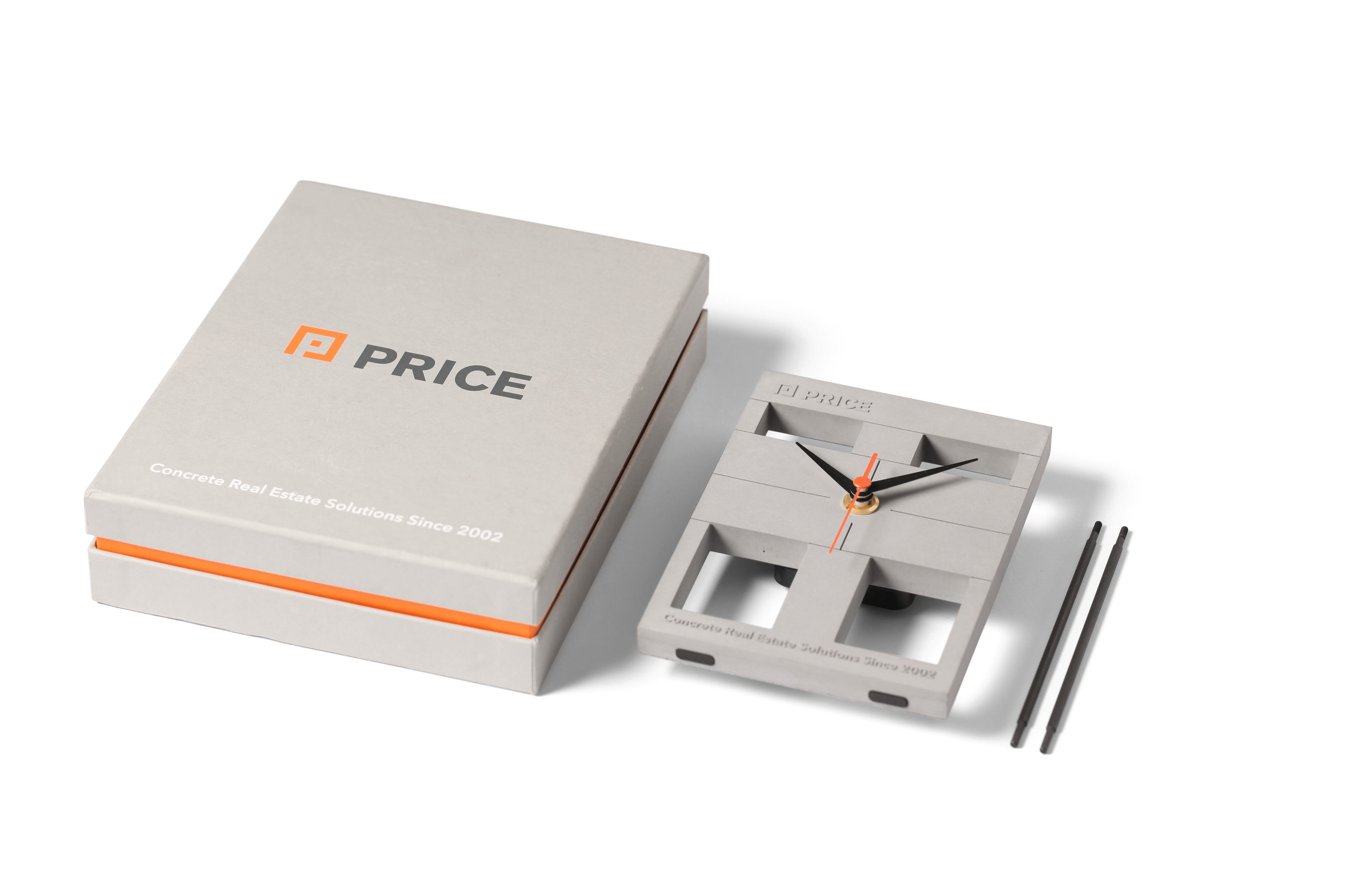 Custom-made concrete desk clock by PRICE, designed for real estate branding. Features minimalist architecture-inspired details, engraved logo and tagline, and premium packaging with bold accents—ideal for corporate gifting and milestone celebrations.
